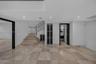 Polished stone flooring, recessed lighting, staircase with metal railings, and contrasting dark-framed doorways
