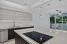 Kitchen featuring high-gloss cabinetry, stone countertops, a stainless steel dishwasher, a built-in cooktop, and recessed tray ceiling lighting