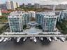 Multi-story residential complex featuring private deep-water boat slips, expansive waterfront sun deck, tiered swimming pool, and glass-railed balconi