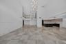 Expansive interior featuring high ceilings, stone flooring, a multi-tiered glass pendant chandelier, a glass-railed mezzanine, and kitchen cabinetry w