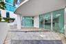 Curved stone patio featuring decorative inlaid tile patterns, expansive floor-to-ceiling glass walls, and a structural concrete support column