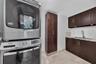 Stacked high-efficiency metallic laundry center, custom dark wood-finish cabinetry, floor-to-ceiling storage pantry, stainless steel undermount sink w