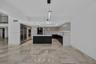 Kitchen featuring high-gloss cabinetry, stone countertops, central island, integrated stainless steel appliances, and large-format tile flooring