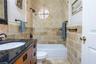 Bathroom featuring natural stone tile walls in a combination of brick-set and diagonal patterns, dark stone-finish vanity countertop, wood-finish cabi