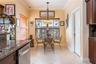 Eat-in kitchen featuring crown molding, ceramic tile flooring, stone-finish countertops, dark wood cabinetry, and a tiered stained-glass pendant light