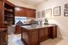 Custom built-in wood cabinetry featuring upper storage units, open shelving, and integrated desk surface with drawer storage, finished with tile floor