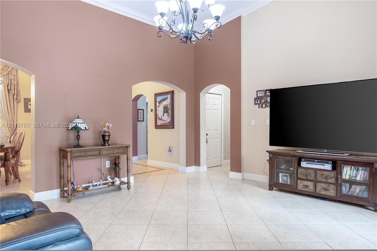 Vaulted ceilings with a decorative chandelier, archway architectural detailing, and tile flooring