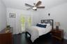 Wood-finish flooring, ceiling fan with integrated lighting, and glass-paned French doors with plantation shutters