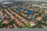 Aerial perspective of a residential property featuring a tile roof, paved driveway, and established landscaping within a suburban community