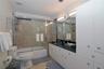 Bathroom featuring a vanity with dark stone countertop, white built-in cabinetry, dual wall-mounted vanity lights, and a tub-shower combination enclos