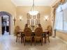 Formal dining area featuring high ceilings, neutral wall tones, tile flooring, crown molding, and a central pendant light fixture