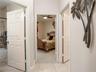 Interior hallway featuring six-panel interior doors, light-colored tile flooring, and a ceiling fan with integrated lighting