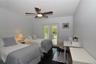 Dark-toned flooring, ceiling-mounted fan with integrated lighting, and glass-paned double doors with slatted shutters