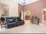 High vaulted ceilings featuring a multi-arm chandelier, neutral ceramic tile flooring, and decorative arched entryways