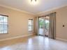 Neutral-toned interior featuring large-format tile flooring, crown molding, double glass-paneled exterior doors, and windows with integrated blinds