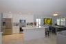 Kitchen featuring white cabinetry, stone-finish island with integrated sink, stainless steel appliances, recessed lighting, and stone flooring