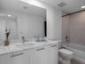 Bathroom featuring a stone-surface vanity with an integrated basin, flat-panel white cabinetry with metallic hardware, a full-width mirror, and a tile
