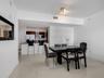 Open floor plan featuring polished tile flooring, kitchen with dark cabinetry, stone countertops, breakfast bar, and recessed track lighting