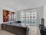 Living area featuring polished tile flooring, full-height glass sliding doors, and an exterior balcony with metal railing