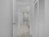 Polished large-format tile flooring, white louvered bifold doors, and a glass-enclosed shower stall