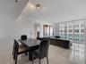 Open-concept interior featuring large-format tile flooring, recessed lighting, and floor-to-ceiling windows with sliding glass door access to a balcon
