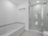 Bathroom featuring a deep soaking tub, separate glass-enclosed shower with tile surround, and built-in wall shelf