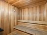 Sauna featuring natural wood-paneled walls and ceiling, tiered wood benches, and integrated wall-mounted analog gauges