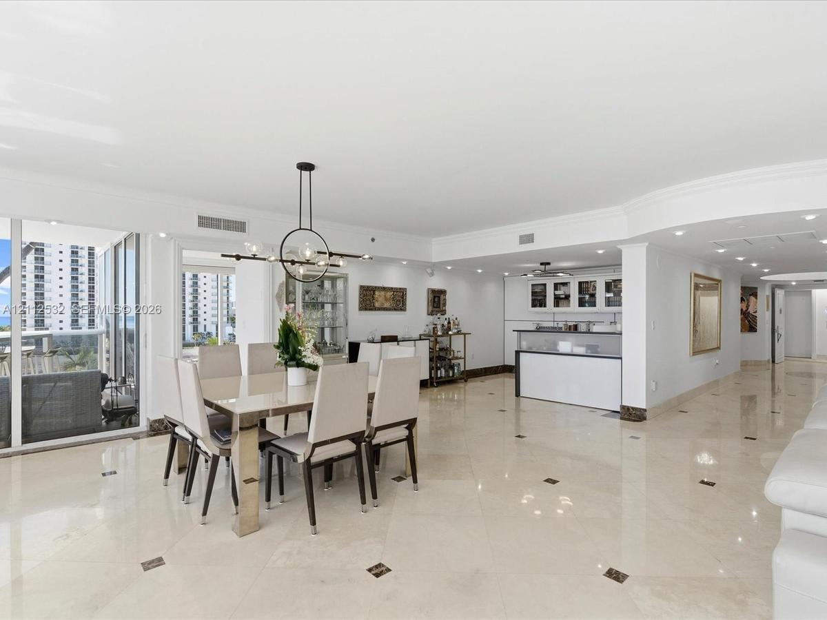Open-concept area featuring polished stone flooring with decorative inlays, a built-in wet bar with cabinetry, recessed lighting, a modern multi-arm c
