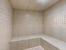 Tiled steam shower featuring built-in bench seating, large-format wall tiles, and decorative basket-weave accent detailing