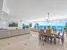 Open-concept floor plan featuring expansive floor-to-ceiling windows, polished stone tile flooring with decorative inlay, recessed lighting, and a mod