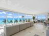 Floor-to-ceiling windows, polished stone tile flooring with decorative inlay, and coastal scenery