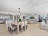 Open-concept interior featuring light-toned stone tile flooring with decorative inserts, floor-to-ceiling glass panel doors, modern geometric multi-li