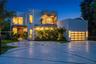 Modern architectural exterior featuring smooth stucco siding, an upper-level glass-railed balcony, a multi-pane glass garage door, and a geometric con