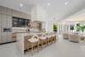 Modern kitchen featuring matte-finish cabinetry, a waterfall-edge stone island, integrated oven and microwave, recessed lighting, and a custom plaster