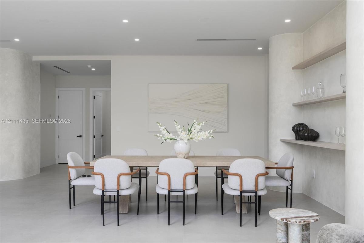 Interior space featuring smooth plaster wall finishes, curved structural columns, integrated wall shelving, recessed ceiling lighting, and solid-core 