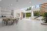 Double-height living area featuring large-format tile flooring, floor-to-ceiling windows, custom built-in recessed shelving, and a floating staircase 