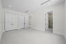 Room featuring smooth flooring, recessed lighting, double-door closet cabinetry, and a doorway revealing a tiled shower enclosure