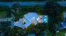 Aerial view featuring a circular concrete driveway, expansive lawn, mature tree canopy, and a rectangular swimming pool with paved terrace