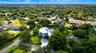 Aerial perspective of a multi-level residence featuring a circular patterned paved motor court, expansive manicured lawn, perimeter landscaping, and a