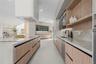 Modern kitchen featuring wood-finish cabinetry, stone countertops, integrated ceiling lighting, a matte black faucet, and a custom range hood