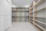 Custom walk-in storage area featuring extensive built-in shelving, integrated hanging rods, crisp white walls, and recessed lighting