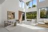 Double-height living area featuring floor-to-ceiling windows, polished concrete flooring, a natural wood entry door, and a floating staircase with int