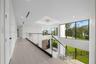 Open landing featuring wood-finish flooring, glass panel railing with metal accents, recessed lighting, and expansive floor-to-ceiling windows