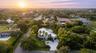 Aerial perspective of a multi-level contemporary residence featuring a flat roofline, circular concrete driveway, private rooftop pool, and mature per
