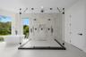Walk-in glass-enclosed shower featuring dual shower heads, a built-in recessed niche, and stone-finish wall tile, paired with a freestanding soaking t