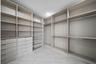 Walk-in closet featuring extensive built-in shelving, integrated multi-drawer cabinetry, dual-level hanging rods, and light-toned tile flooring