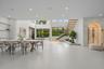 Open-concept living space featuring large-format tile flooring, a floating staircase with glass railings, built-in recessed shelving, a glass-enclosed