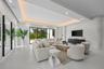 Living area featuring a coffered ceiling with integrated cove lighting, recessed ceiling lights, a textured stone-finish accent wall, and multi-panel 
