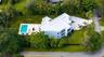 Modern multi-level estate featuring a flat-roof architectural design, a private swimming pool with an integrated spa, expansive lawn, and a decorative