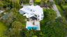 Multi-level residence featuring a flat roofline, minimalist white exterior, covered rear terrace, private swimming pool, and stone pool deck